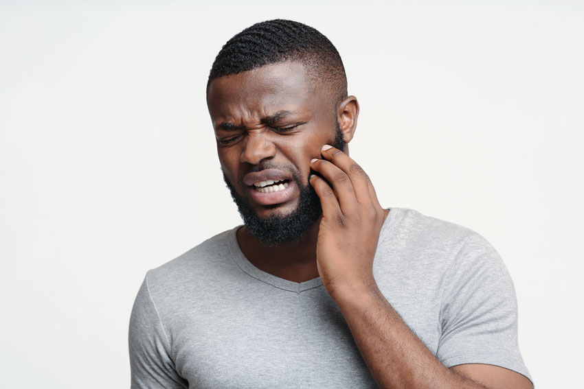 adult man holding jaw in pain